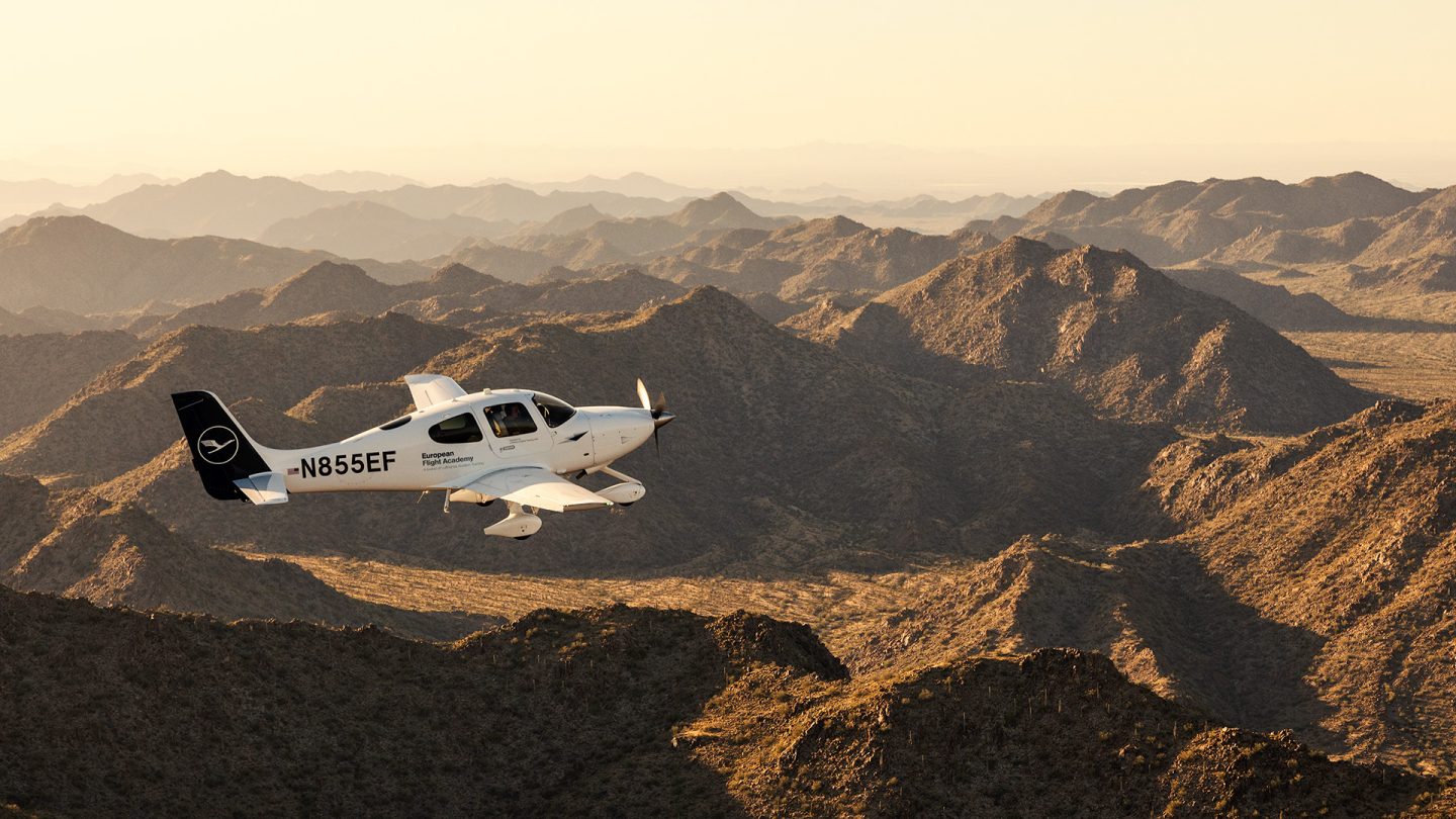 A training aircraft glides over Arizona's impressive mountain landscape in the evening light.