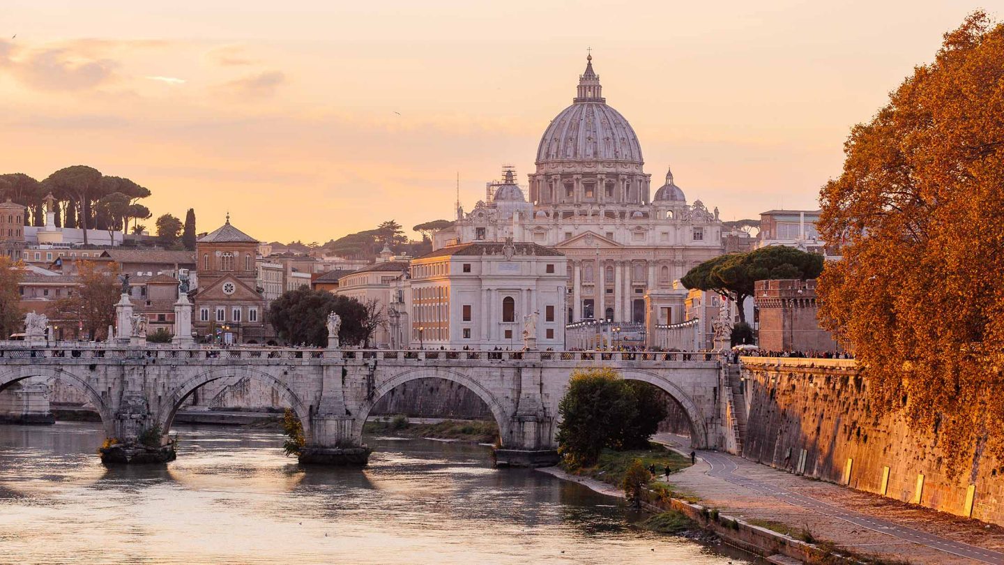 View of St. Peter’s Basilica in Rome at sunset with autumn riverside