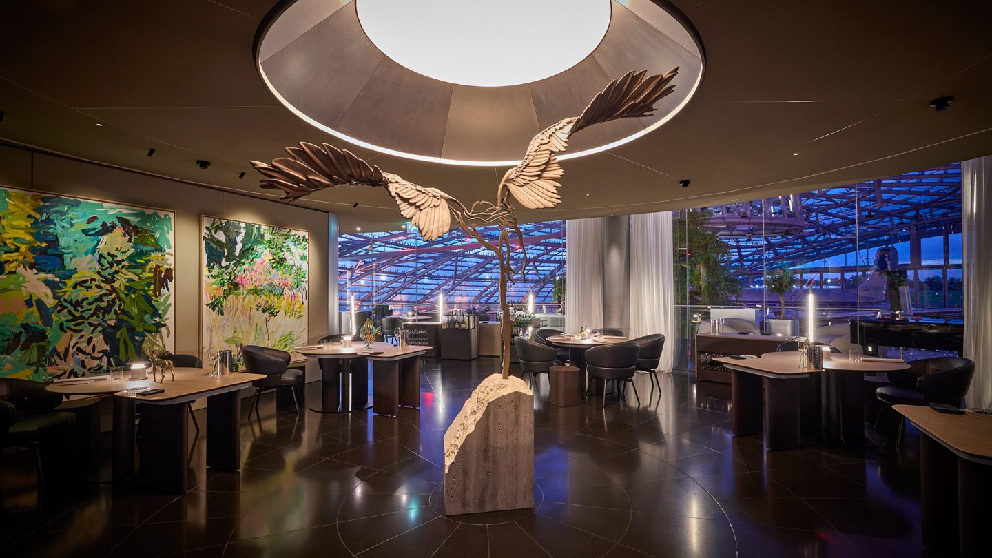 Modern restaurant Ikarus im Hangar-7 in Salzburg featuring a large bird sculpture in the center and colorful abstract art 